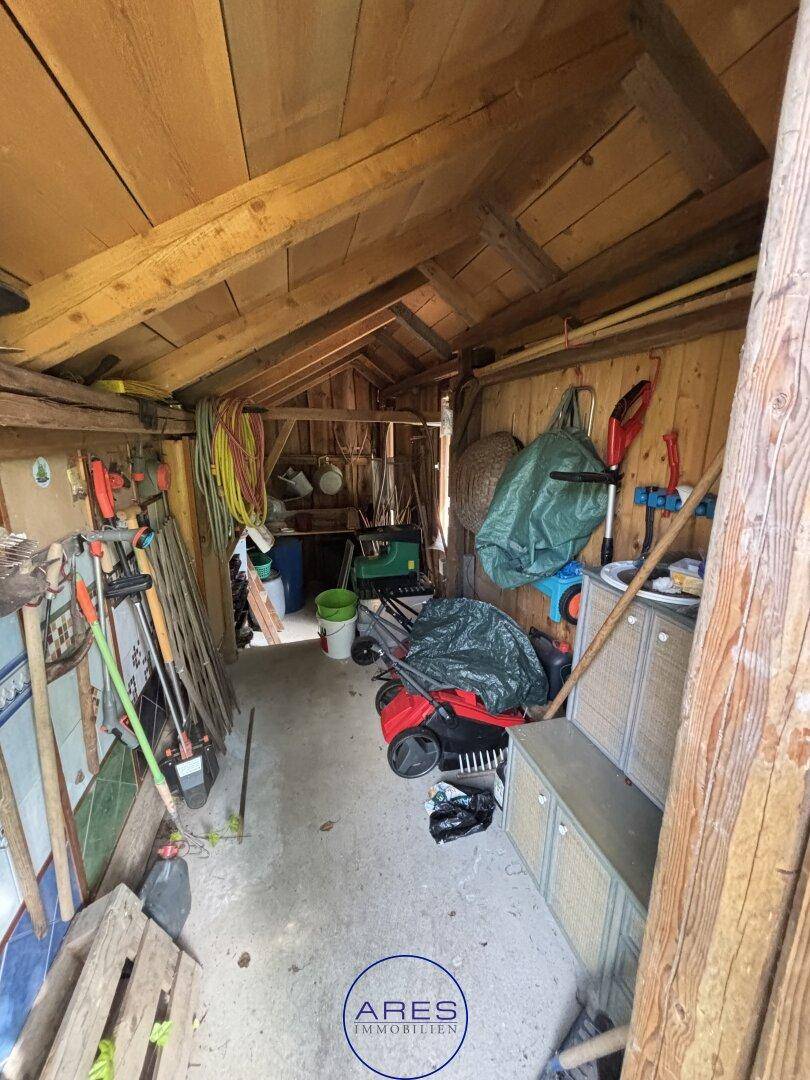 Innenansicht eines Holzschuppens, der als Abstellraum für Gartengeräte und Werkzeuge dient.