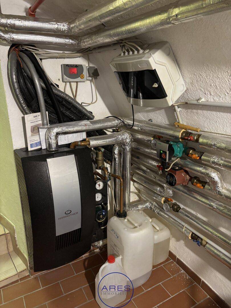 Heizungsanlage mit zahlreichen Rohrleitungen und einem Boiler in einem Technikraum im Keller.