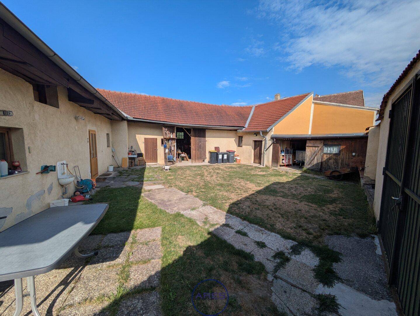 Innenhof des Anwesens mit Grasflächen und Betonwegen, umgeben von verschiedenen Gebäuden.