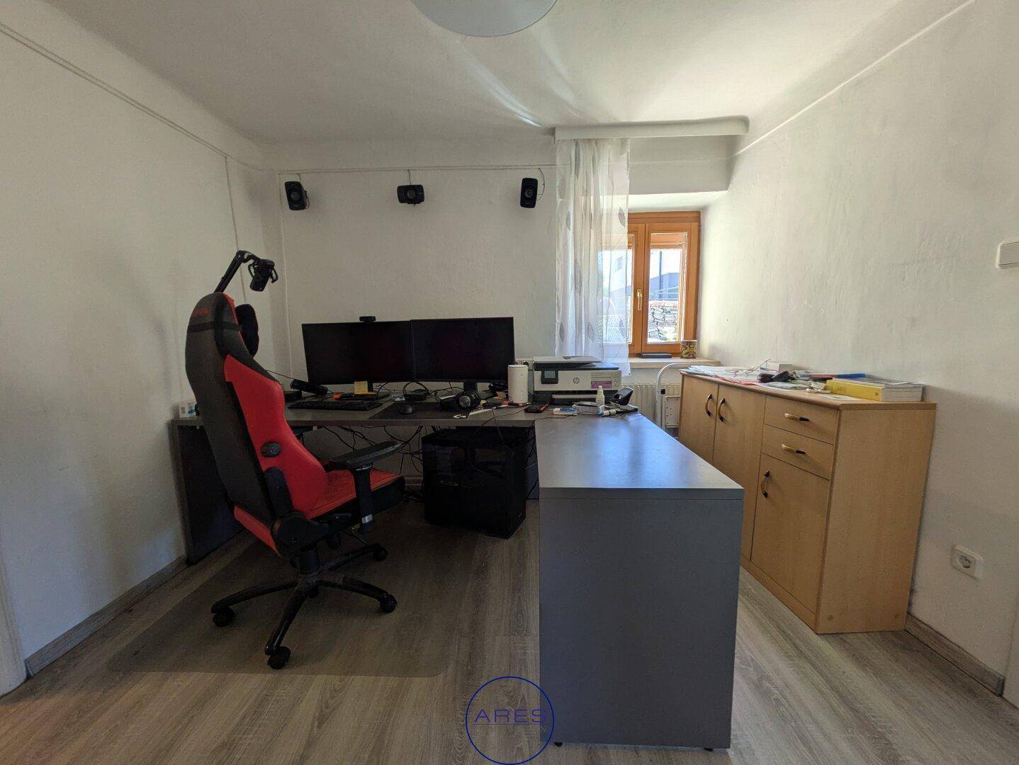 Arbeitszimmer mit Schreibtisch, Computermonitoren und hellem Laminatboden.