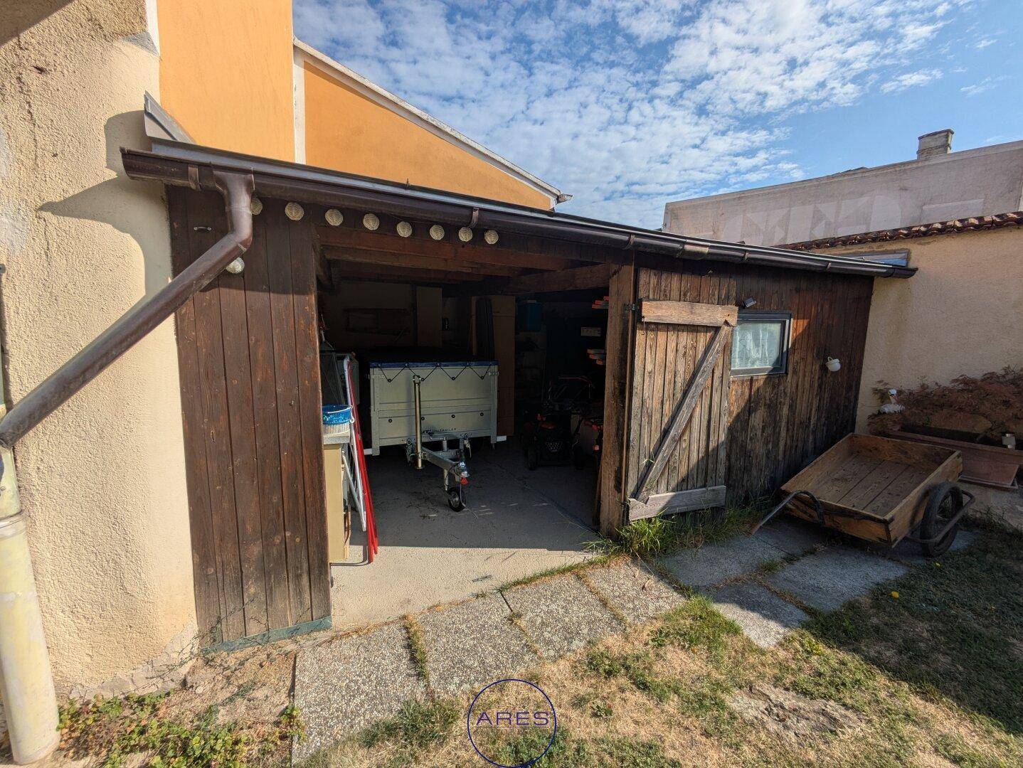 Hölzerner Schuppen oder Garage mit einem Anhänger darin.