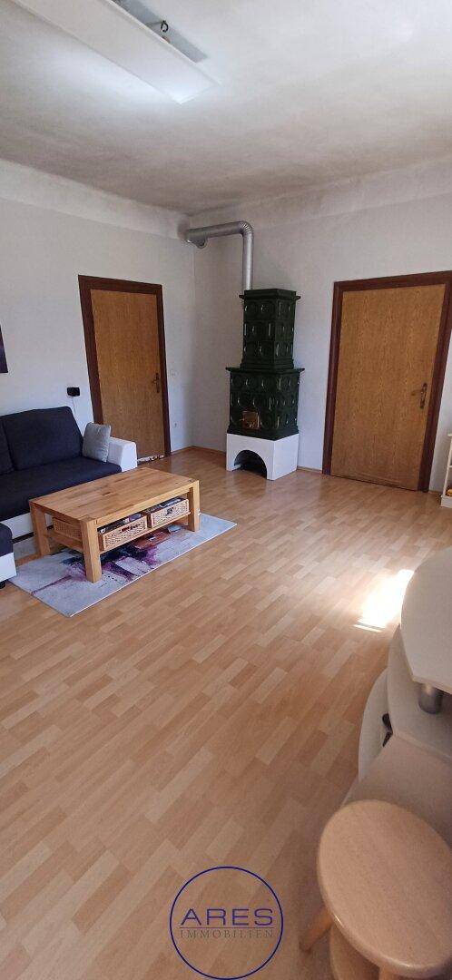 Gemütliches Wohnzimmer mit traditionellem Kachelofen und hellem Holzfußboden.