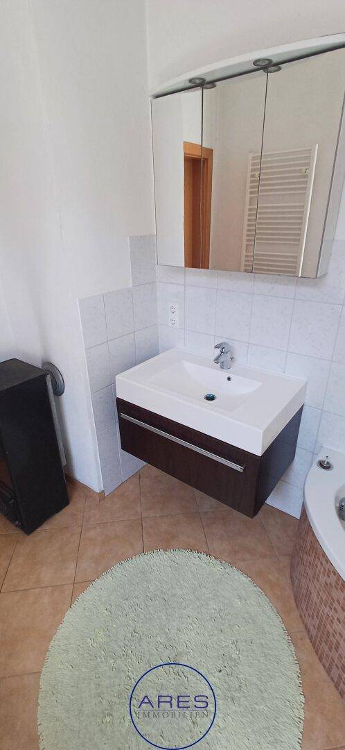 Modernes Badezimmer mit Waschtisch, Spiegelschrank und Fliesenboden.