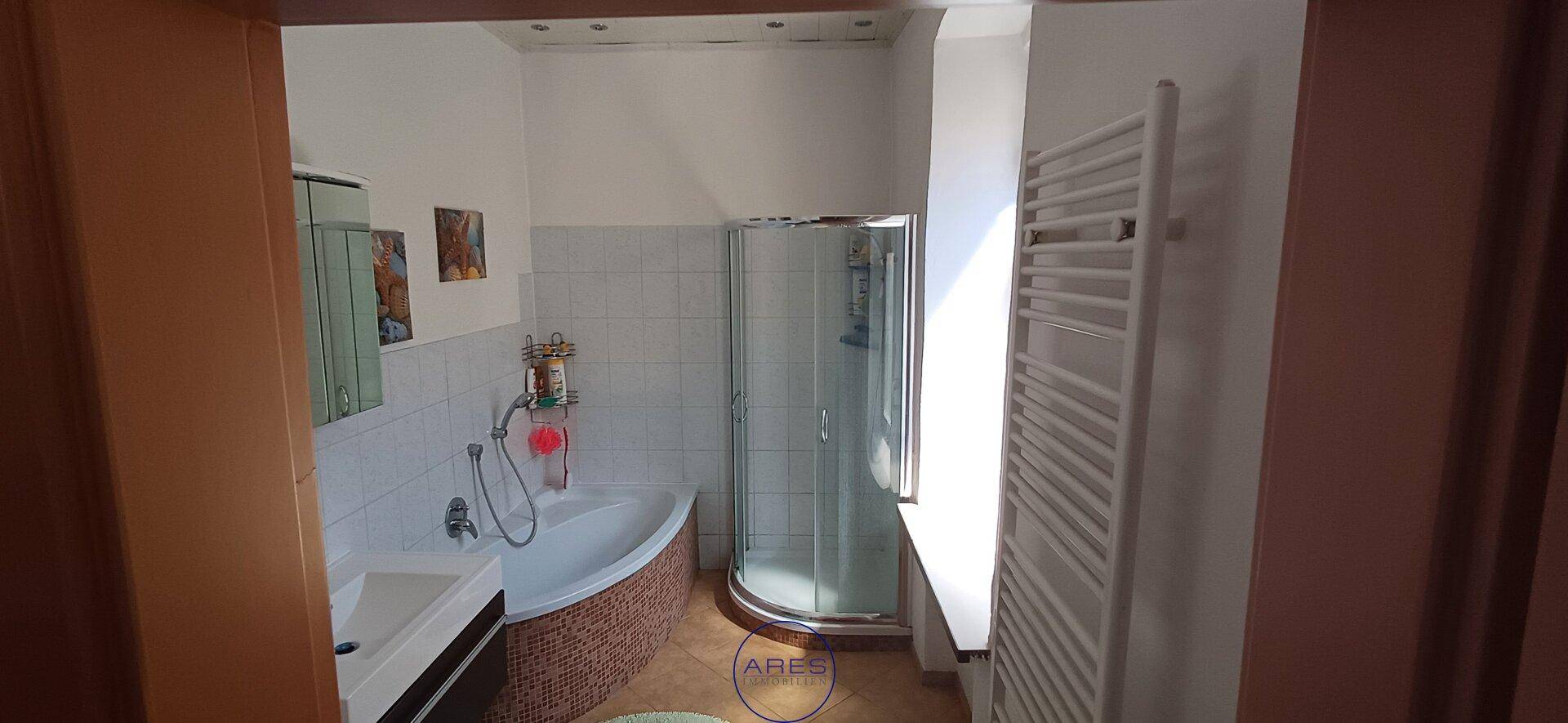 Badezimmer mit Badewanne, Duschkabine und beheiztem Handtuchhalter.