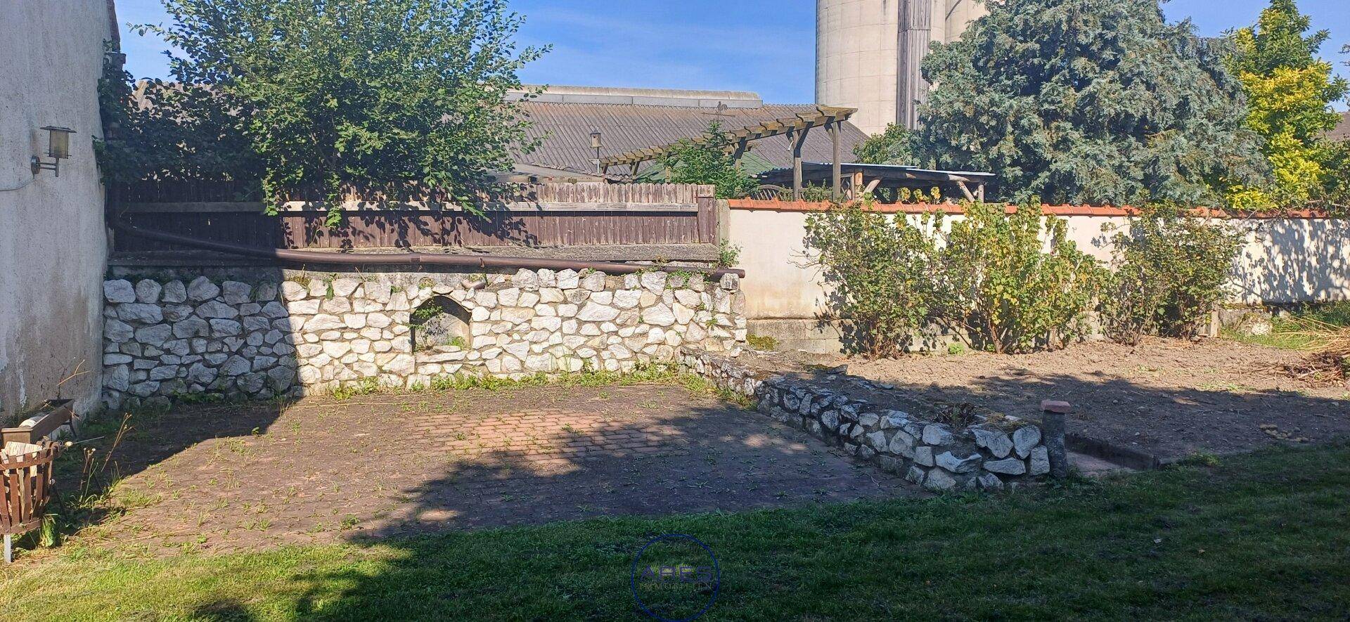 Gartenbereich mit Natursteinmauern und vorbereiteten Beeten für Pflanzen.