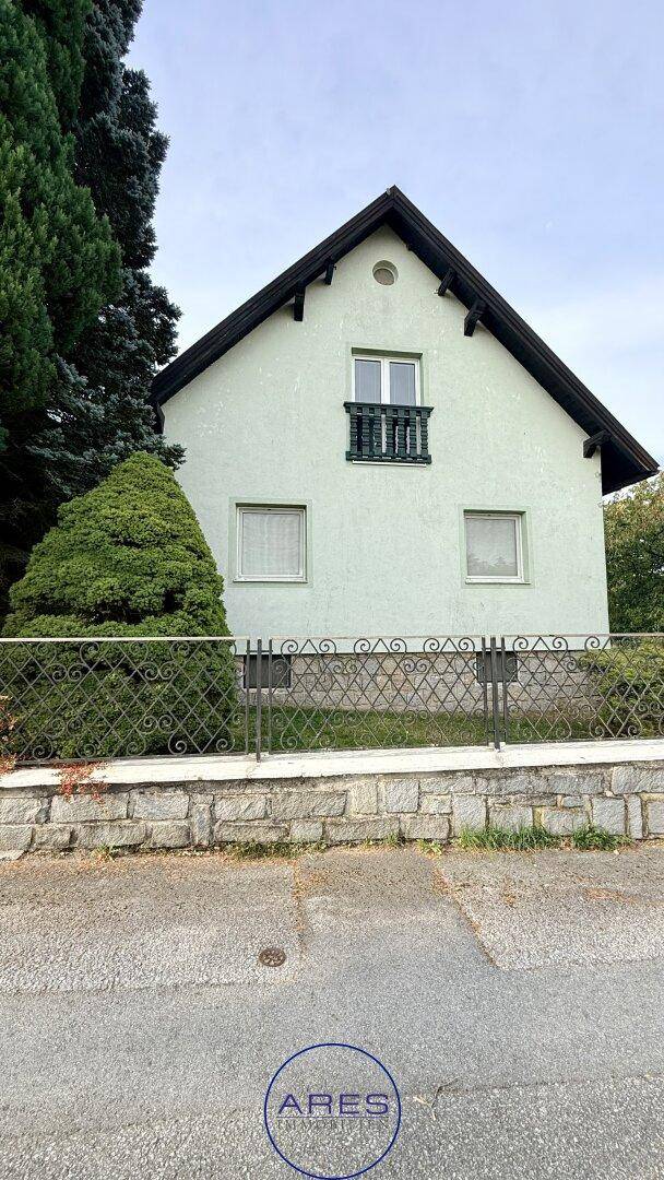 Vorderansicht des Hauses von der Straße aus mit Zaun und kleinem französischen Balkon im Obergeschoss.