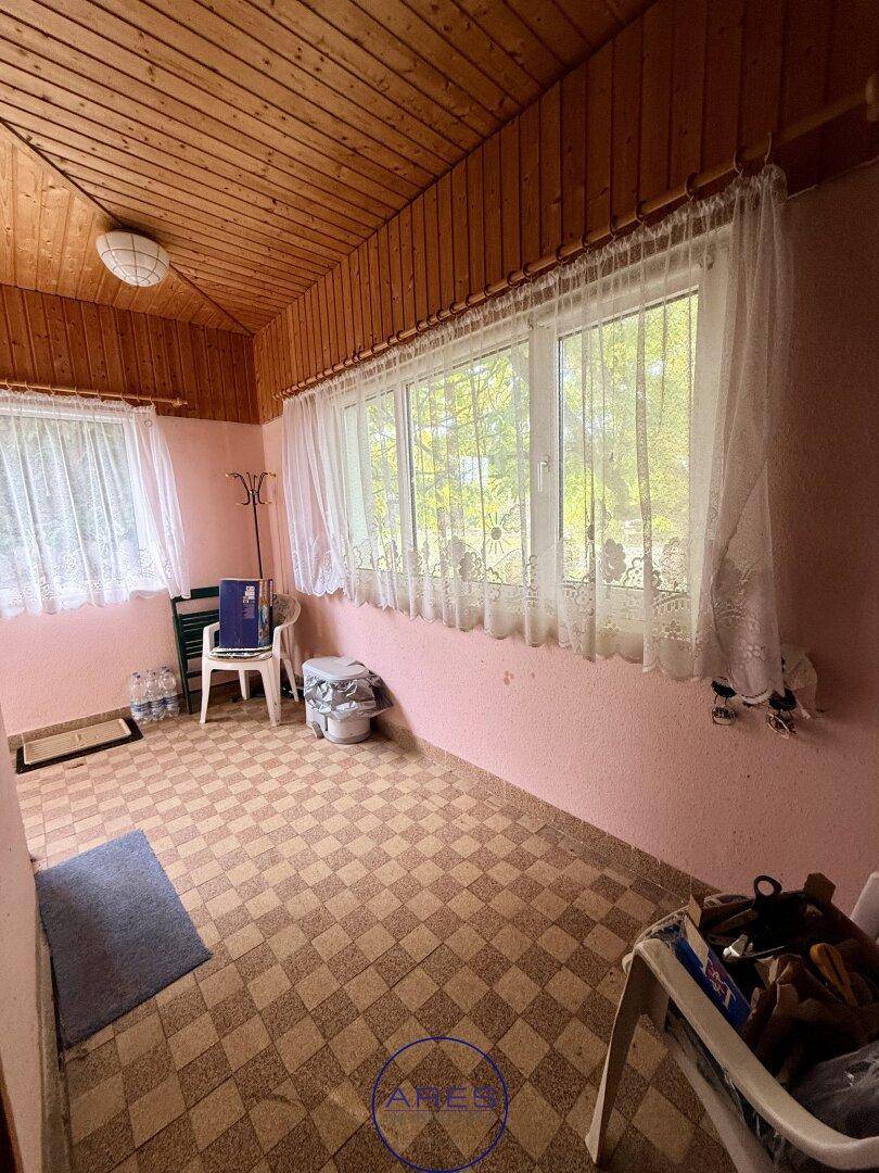 Heller Wintergarten mit Holzdecke und kariertem Fliesenboden, bietet viel Tageslicht durch große Fenster.
