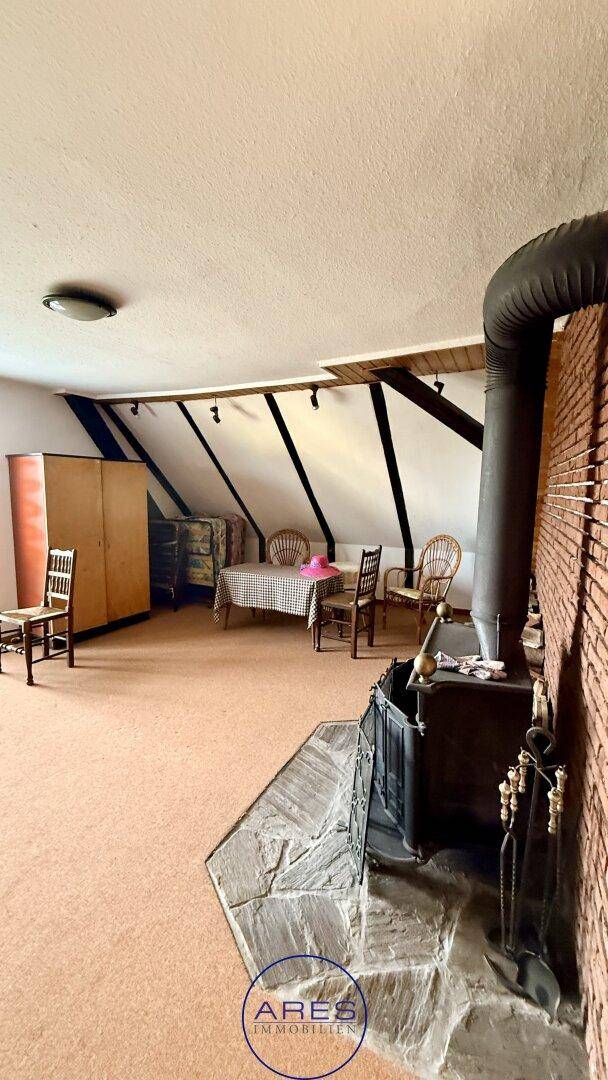 Wohnbereich im Dachgeschoss mit einem traditionellen Holzofen, Ziegelwand und rustikalen Möbeln.