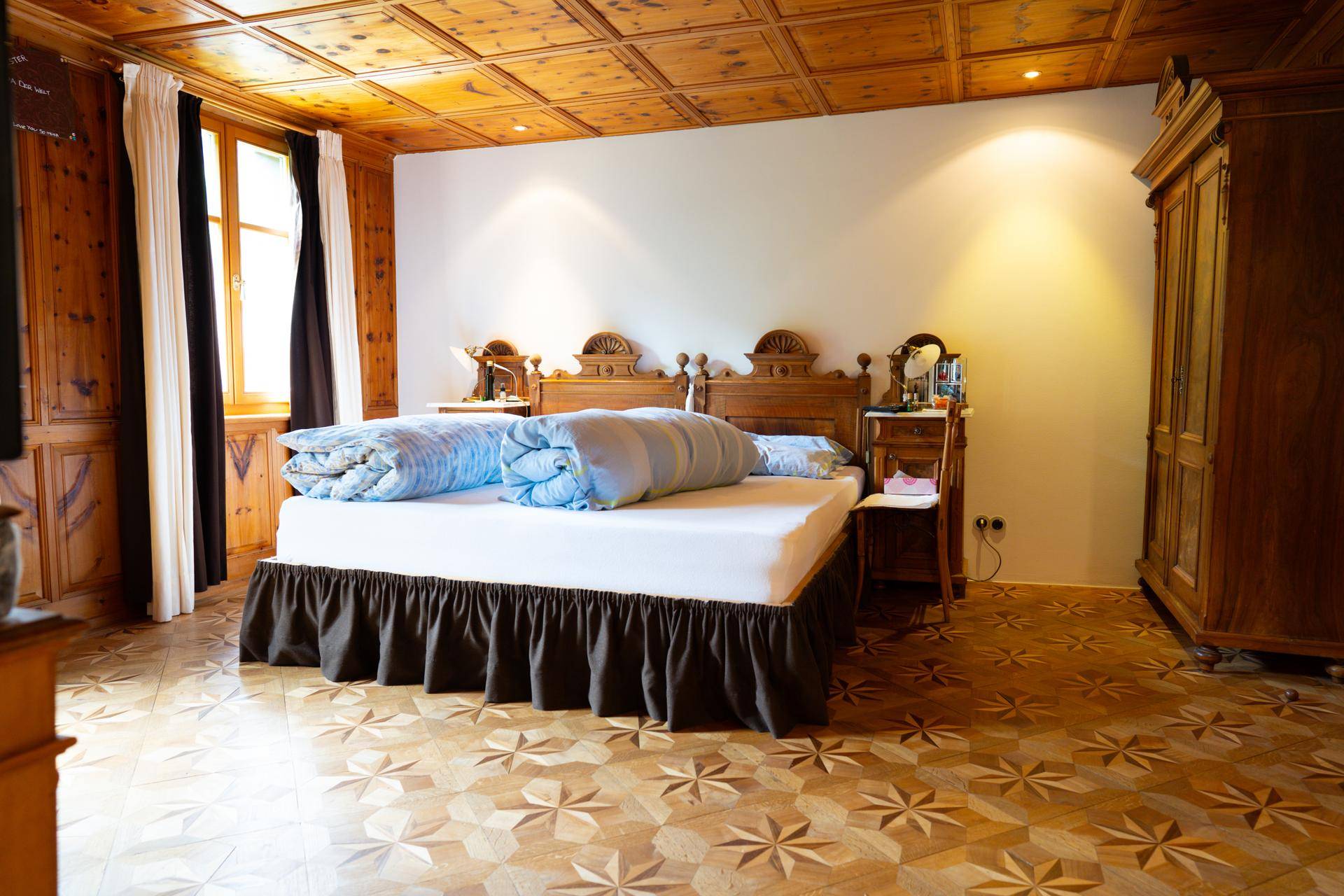 Gemütliches Schlafzimmer mit Doppelbett, Holzboden und traditioneller Kassettendecke.
