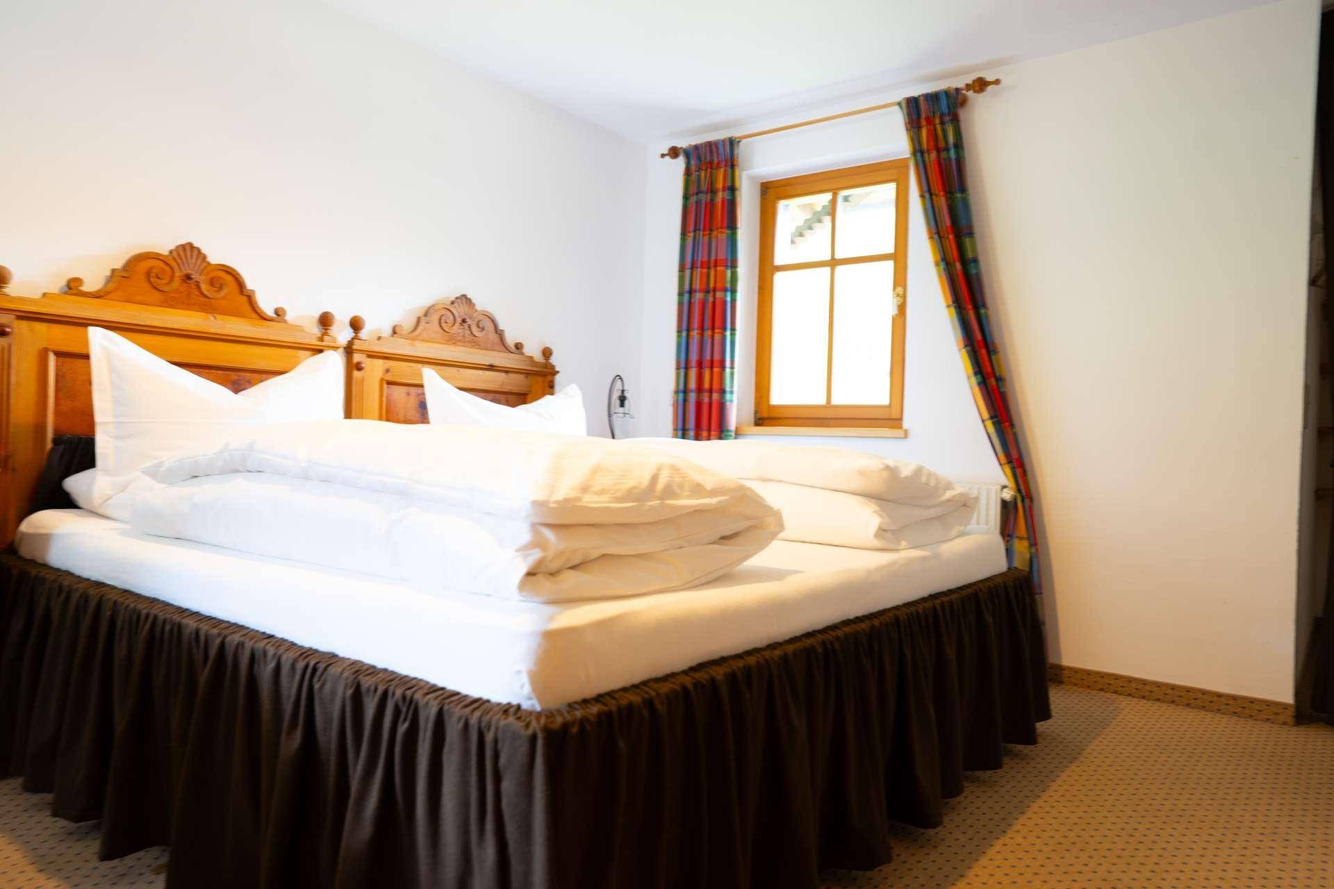 Helles Schlafzimmer mit Holzbett, Teppichboden und farbenfrohen Vorhängen.