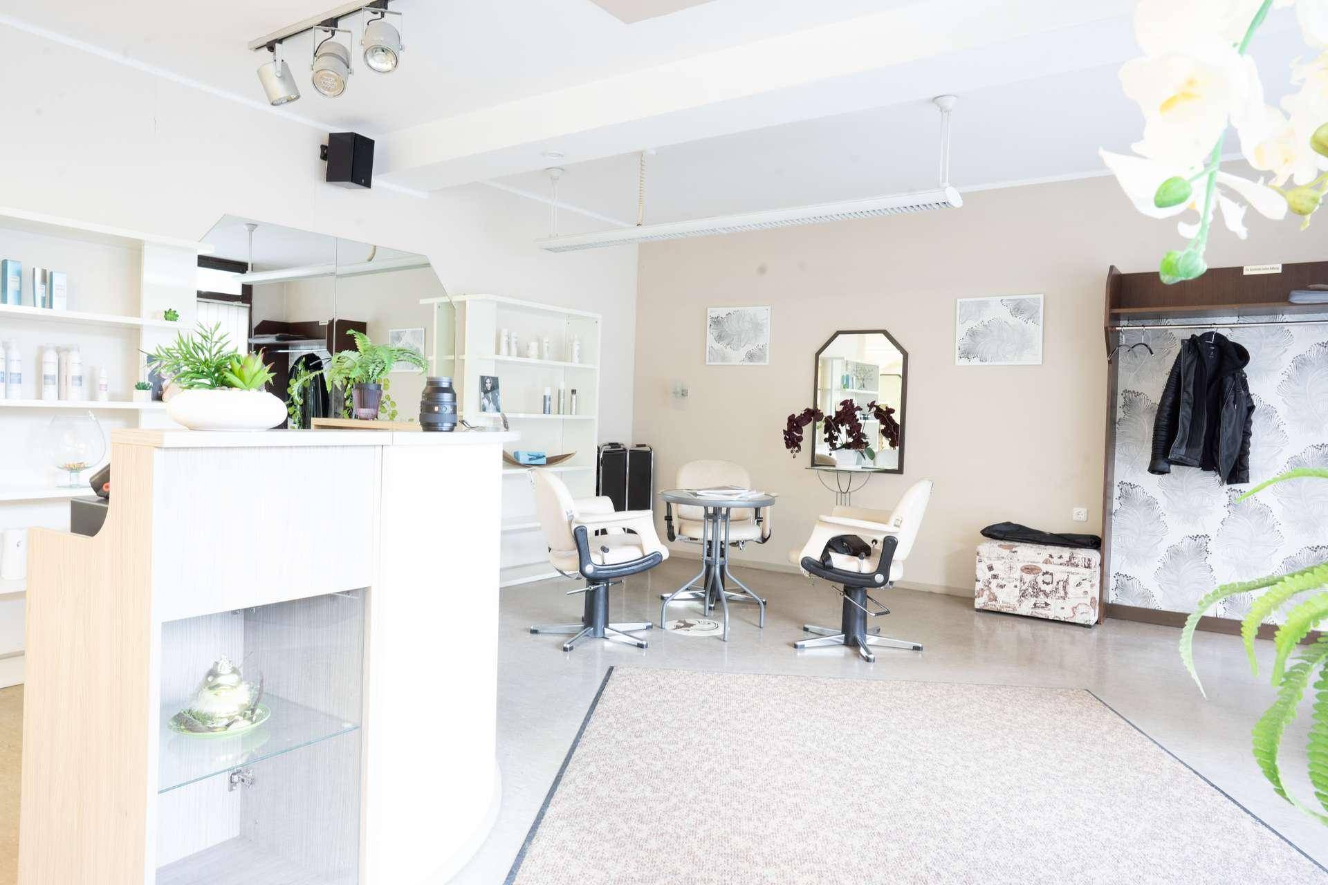 Heller Empfangsbereich eines Salons mit Sitzgelegenheiten, Spiegeln und Pflanzen, ausgestattet mit Fliesenboden.