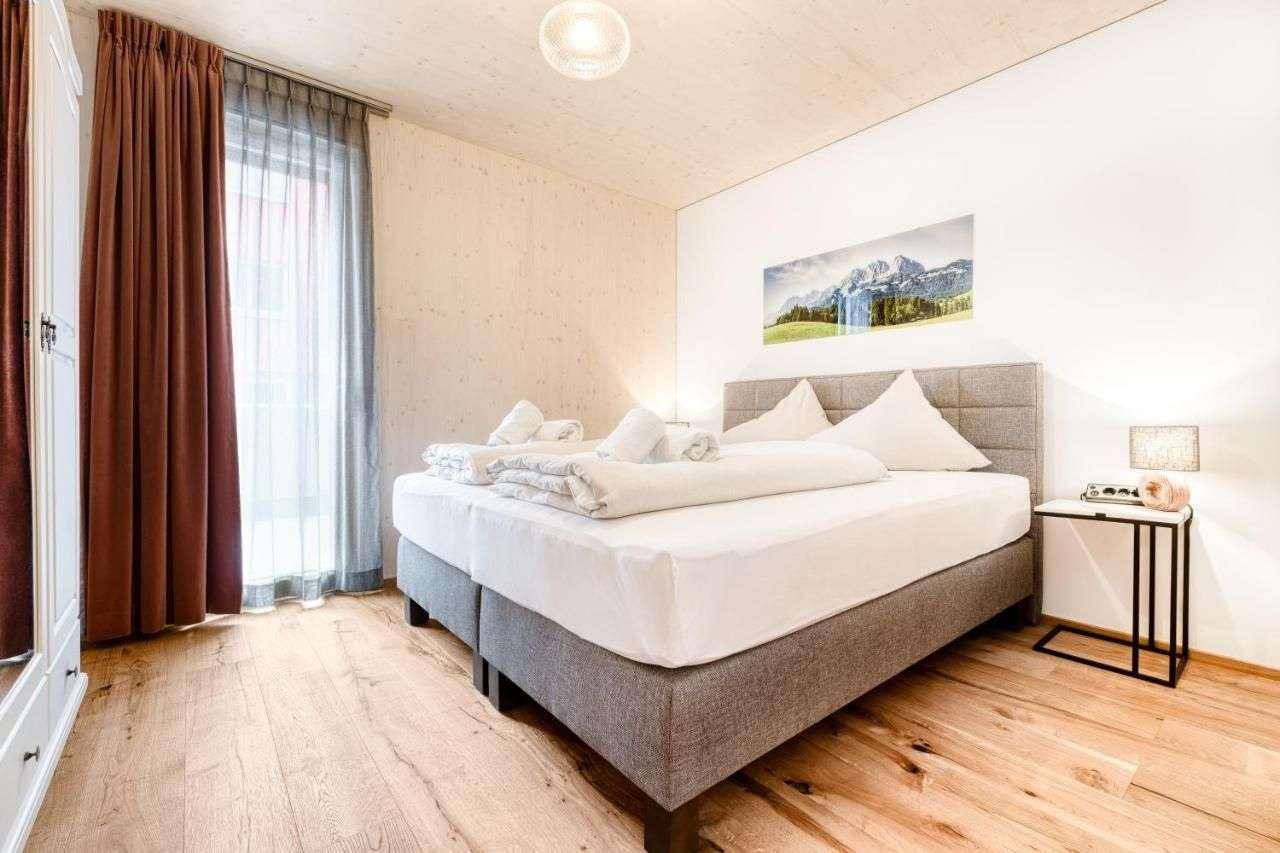 Gemütliches Schlafzimmer mit Doppelbett, Holzboden und Zugang zum Balkon.