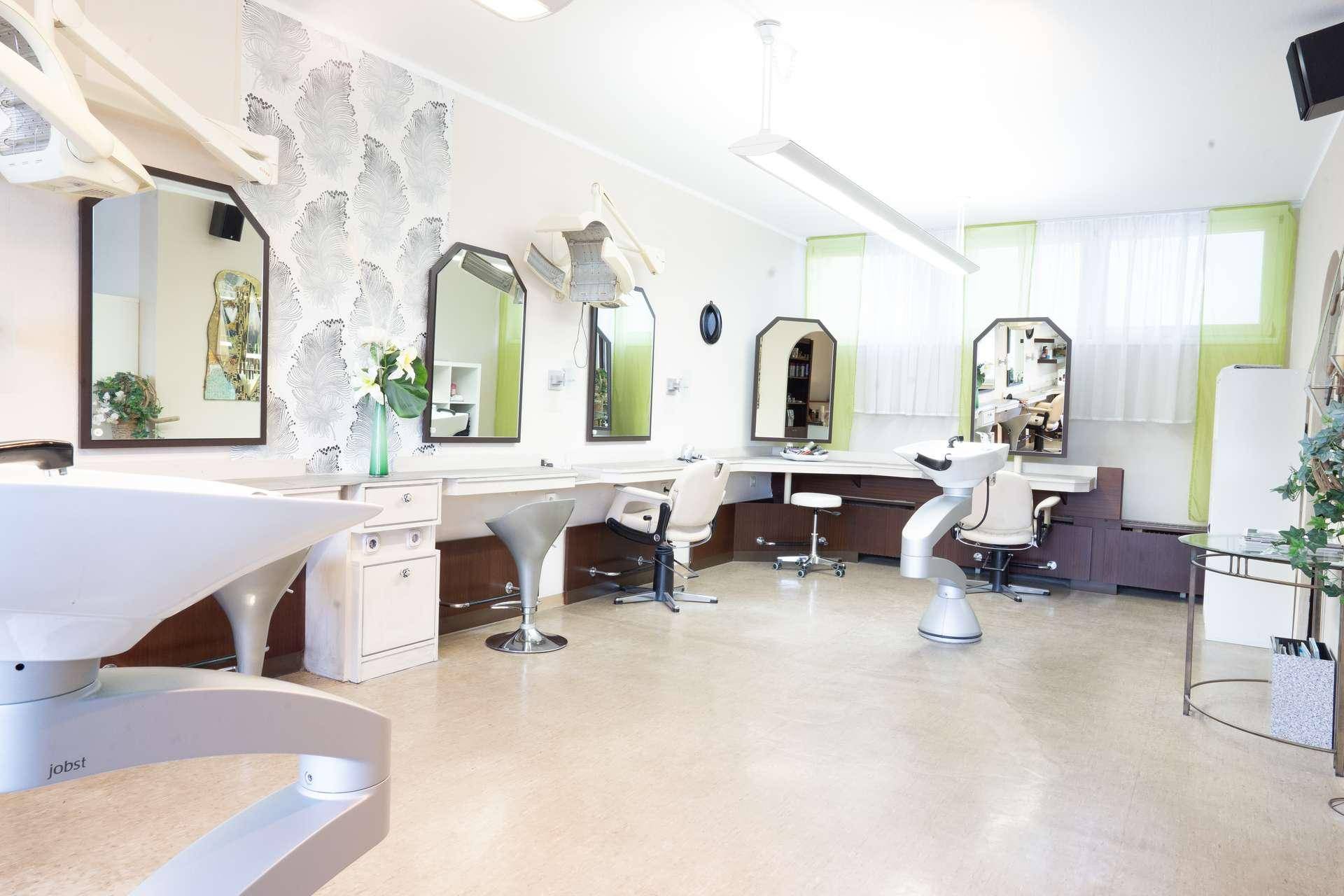 Geräumiger Friseursalon mit mehreren Arbeitsplätzen, Spiegeln und Waschbecken, hell und funktional eingerichtet.