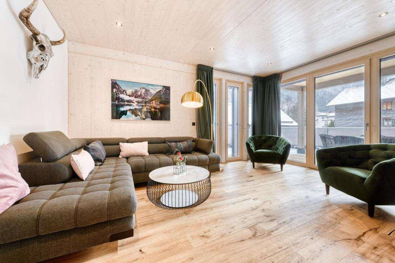 Gemütliches Wohnzimmer mit großem Sofa, Holzboden und Zugang zum Balkon.