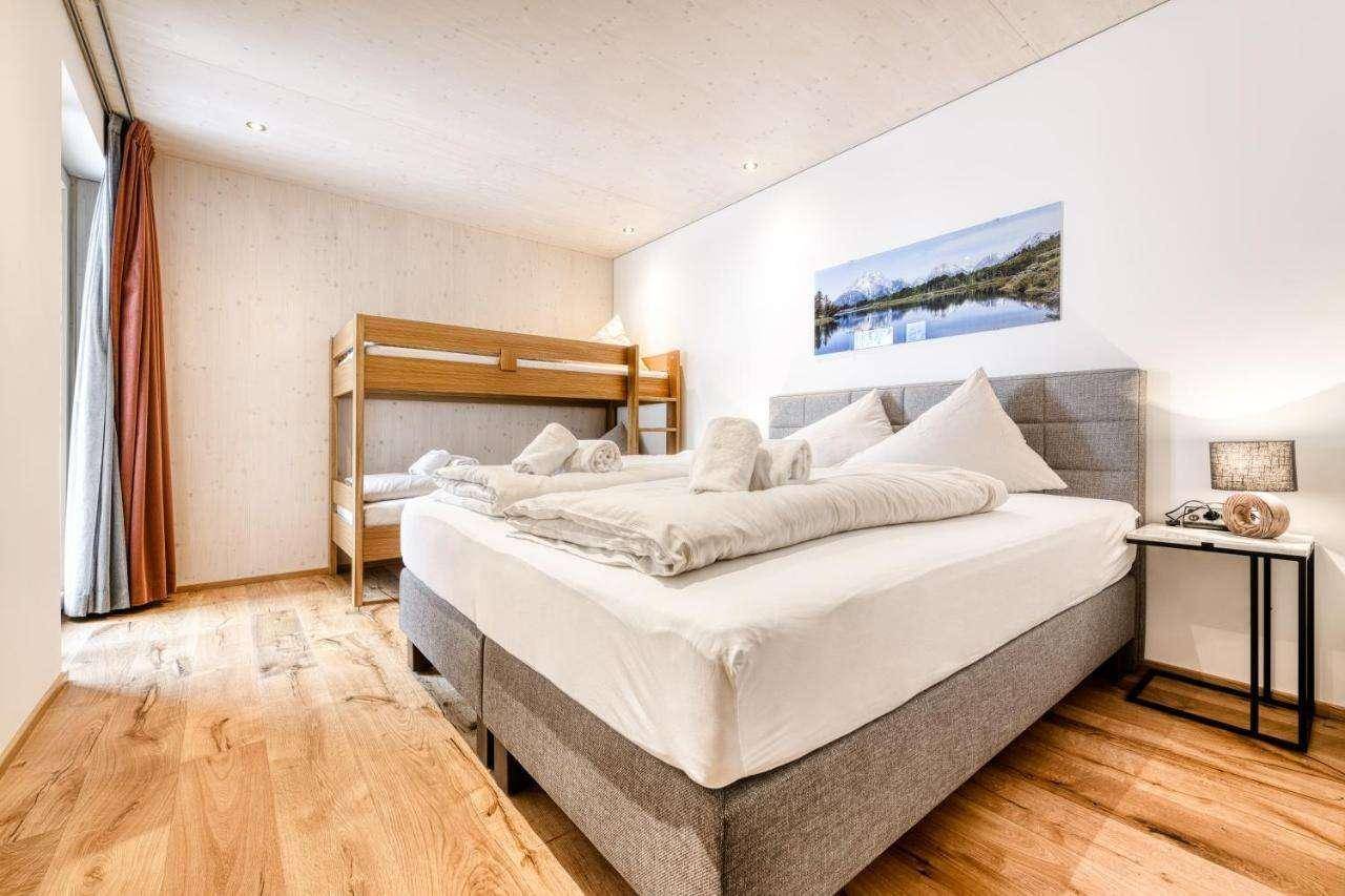 Helles Schlafzimmer mit Doppelbett, Etagenbett und Holzboden.