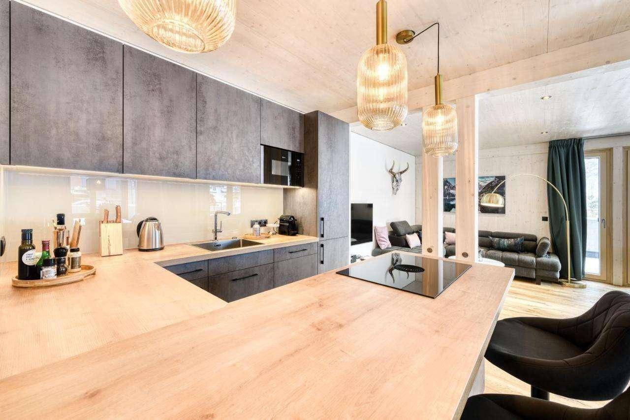Moderne Küche mit Holztheke, grauen Schränken und offener Verbindung zum Wohnbereich.