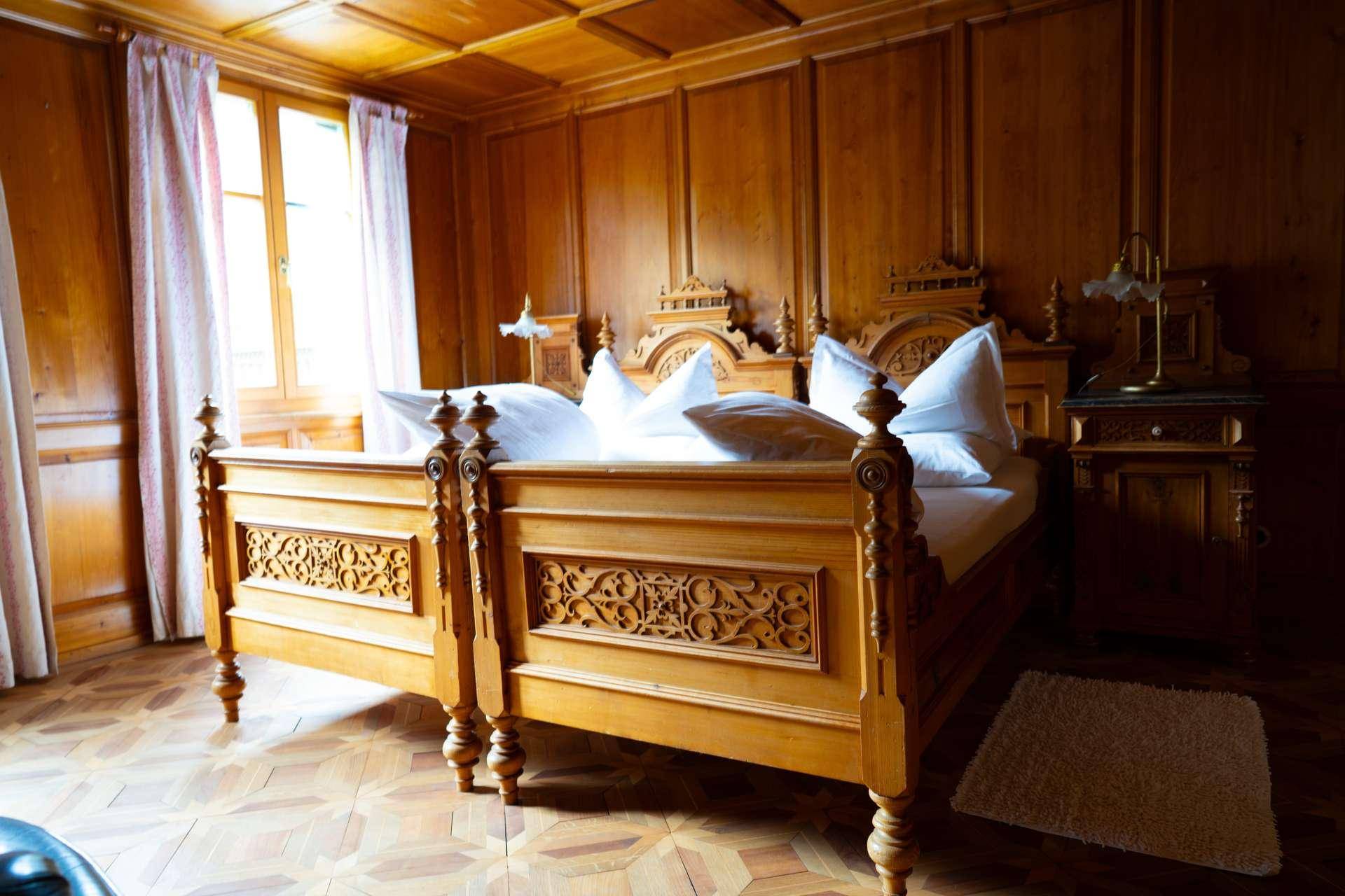 Traditionelles Schlafzimmer mit kunstvoll geschnitztem Holzbett und Holztäfelung.