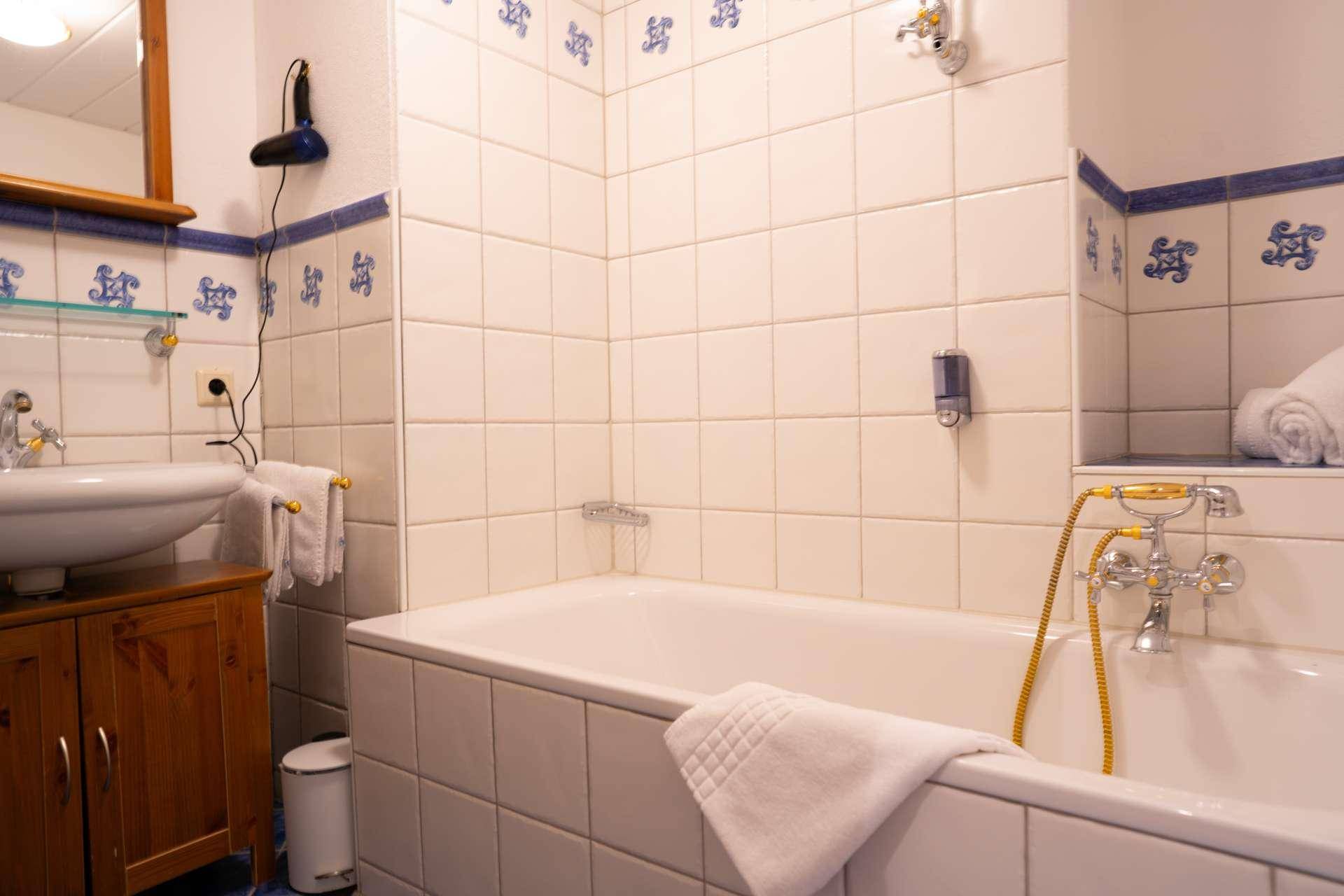 Badezimmer mit Badewanne, Fliesen und traditionellen blauen Dekorelementen.