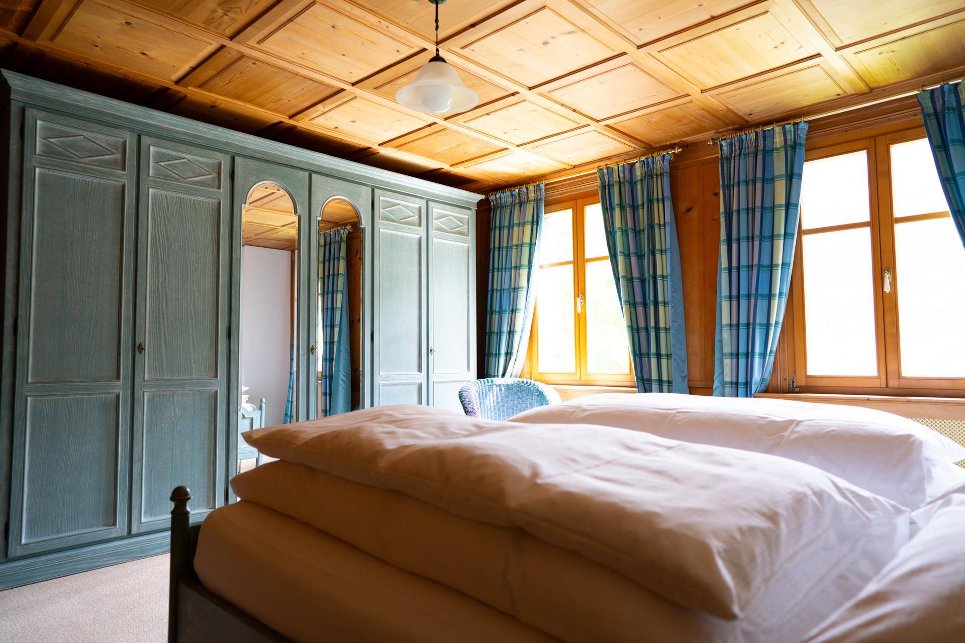 Geräumiges Schlafzimmer mit großem Kleiderschrank, Doppelbett und Holzdecke.