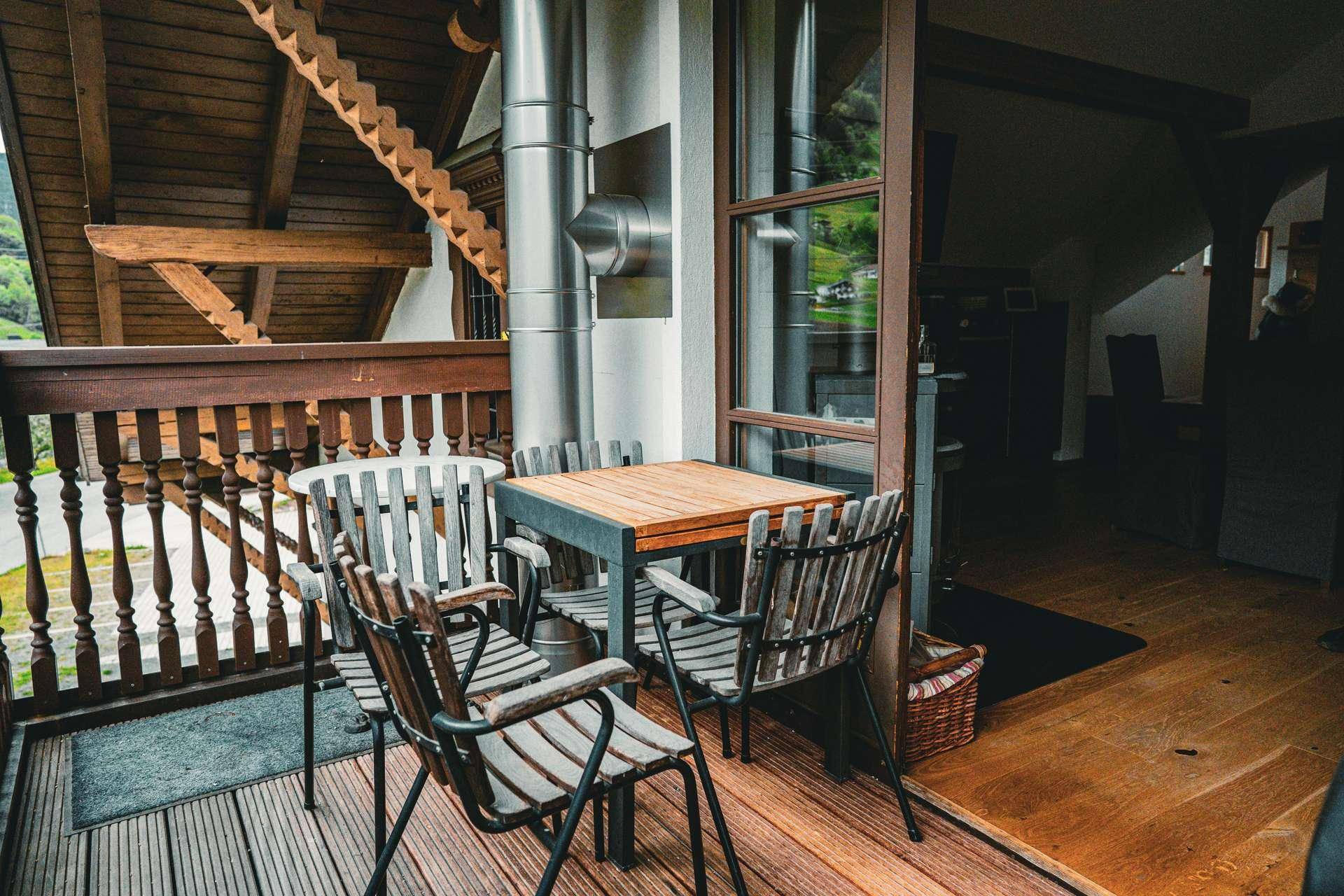 Gemütlicher Balkon mit Holzboden und Sitzgelegenheiten, umgeben von alpiner Holzarchitektur.
