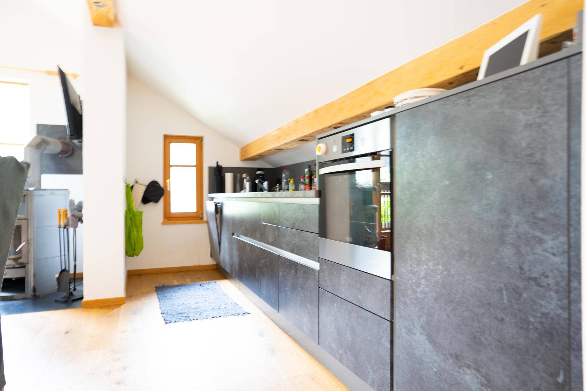 Moderne Küche mit dunklen Schränken, Einbaugeräten und Holzbalken.