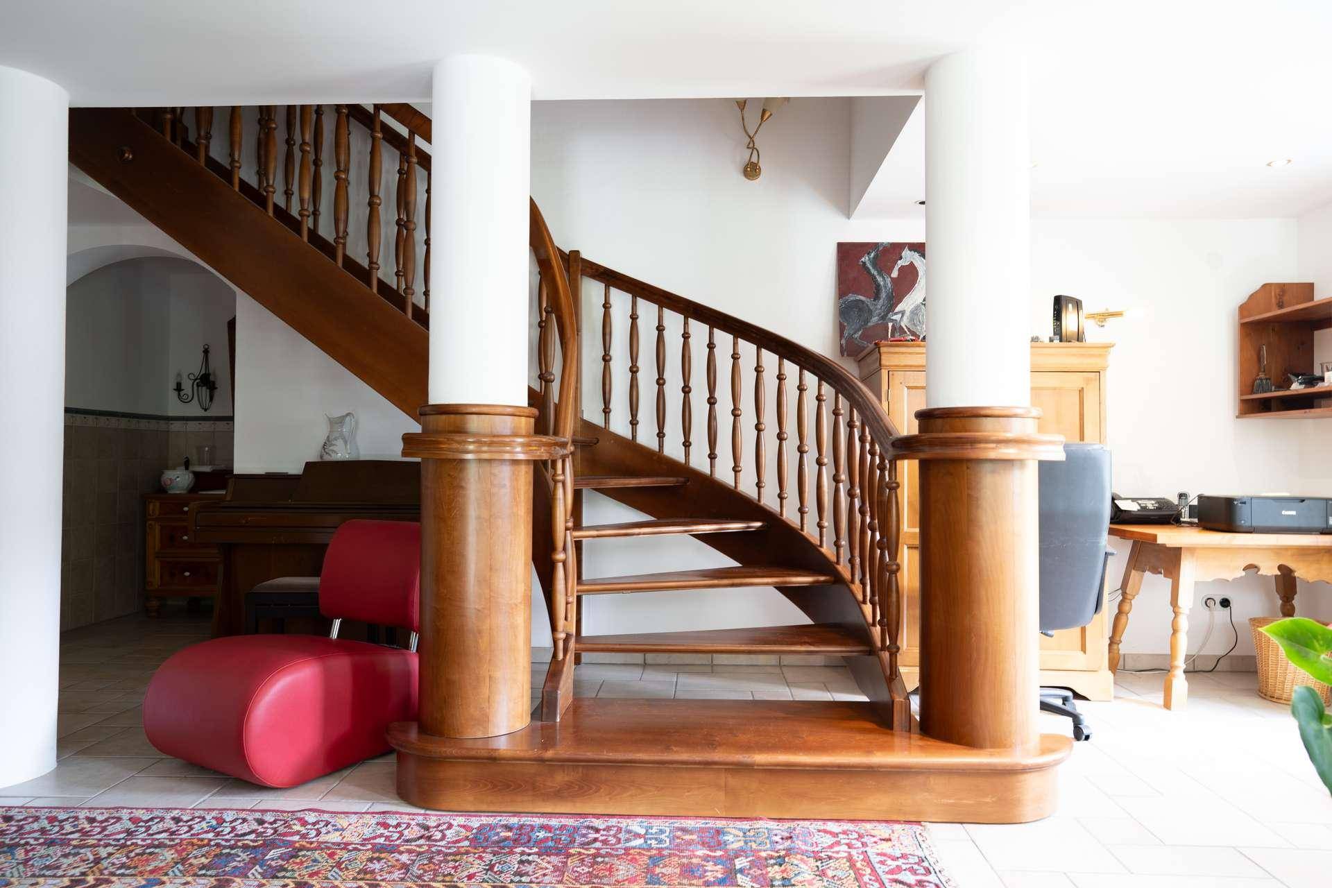 Elegante Holztreppe mit geschwungenem Geländer in einem hellen Eingangsbereich.