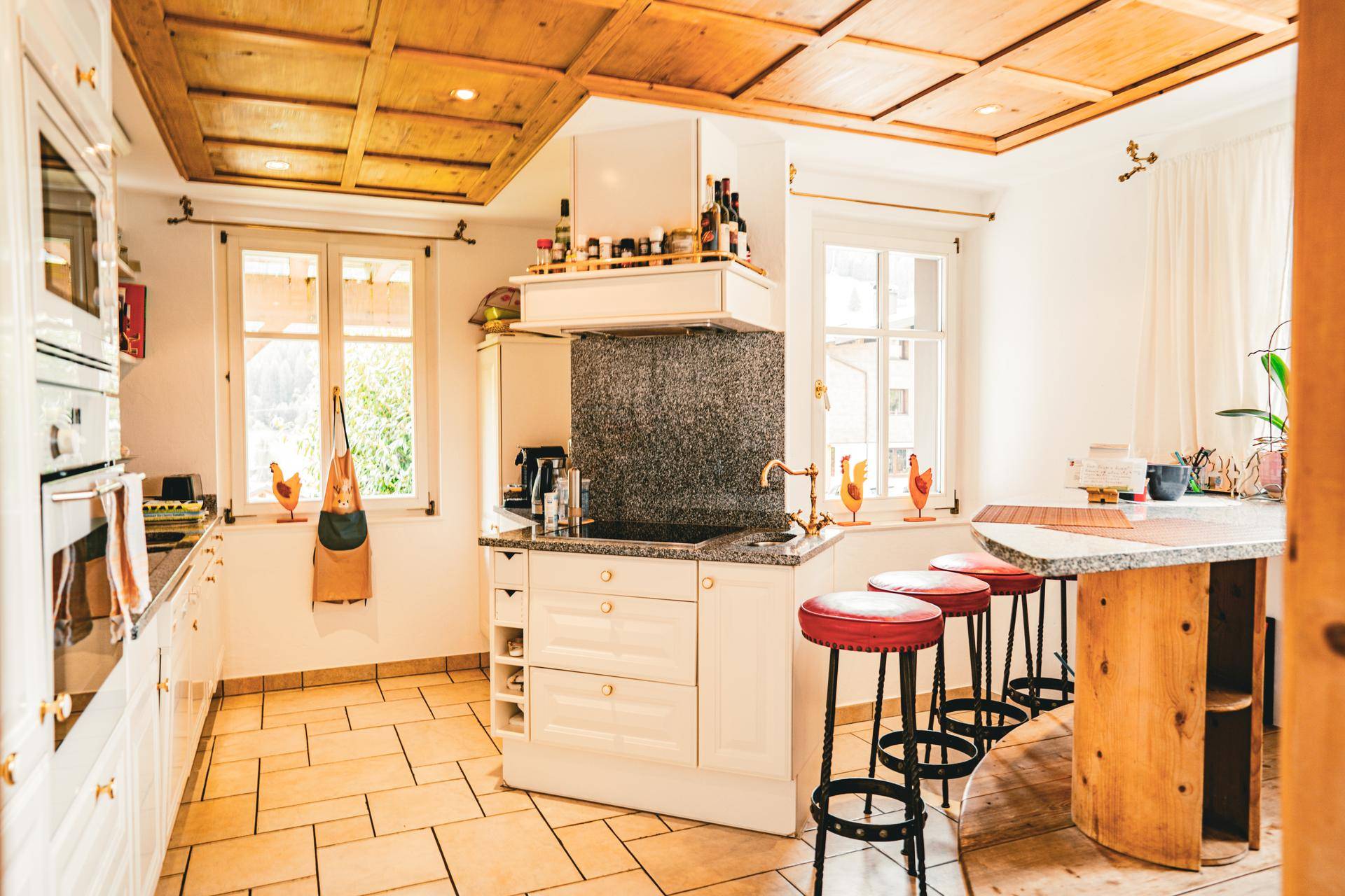 Geräumige Küche mit Kochinsel, Barhockern und traditioneller Holzdecke, ideal für geselliges Kochen.