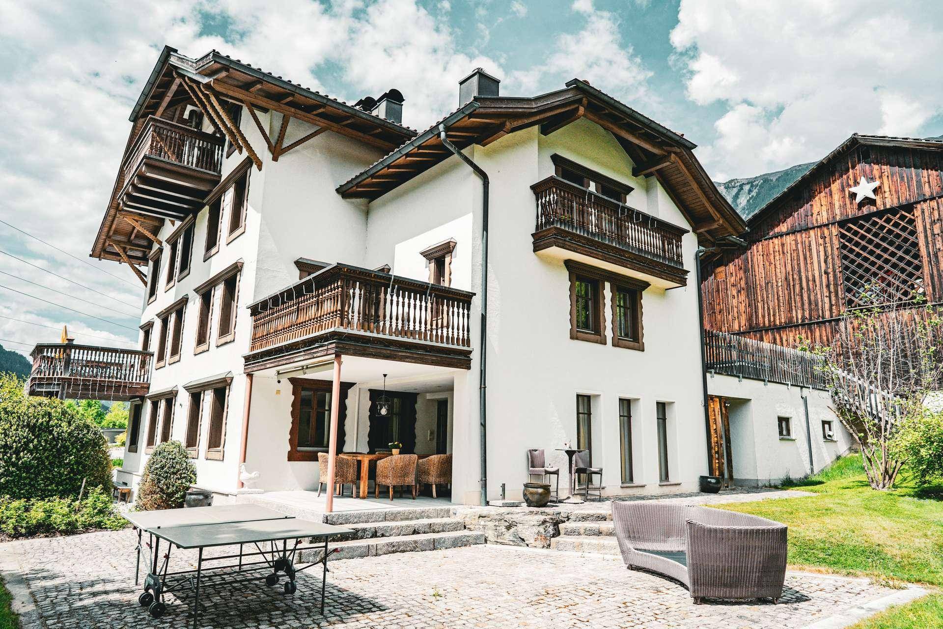 Große Terrasse mit Sitzgelegenheiten und Tischtennisplatte, umgeben von grüner Landschaft.