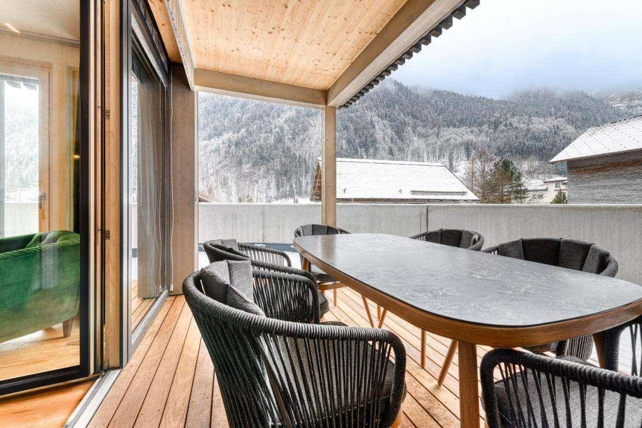 Geräumiger Balkon mit Holzboden, Esstisch und Bergblick.