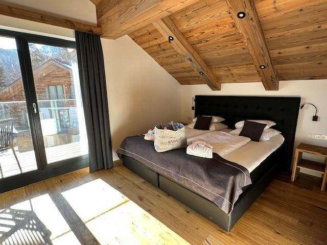 Gemütliches Schlafzimmer mit Doppelbett, Holzbalkendecke und Balkonzugang mit Bergblick.