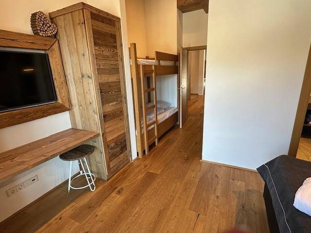 Geräumiges Schlafzimmer mit Doppelbett, Etagenbetten und Holzbalkendecke.