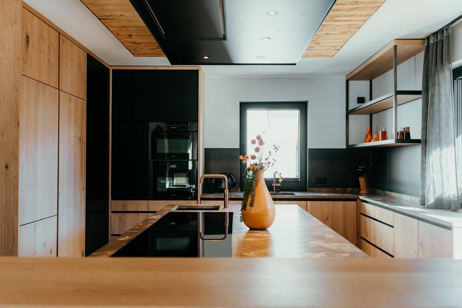 Moderne Küche mit Holzfronten, Kochinsel und hochwertigen Einbaugeräten.