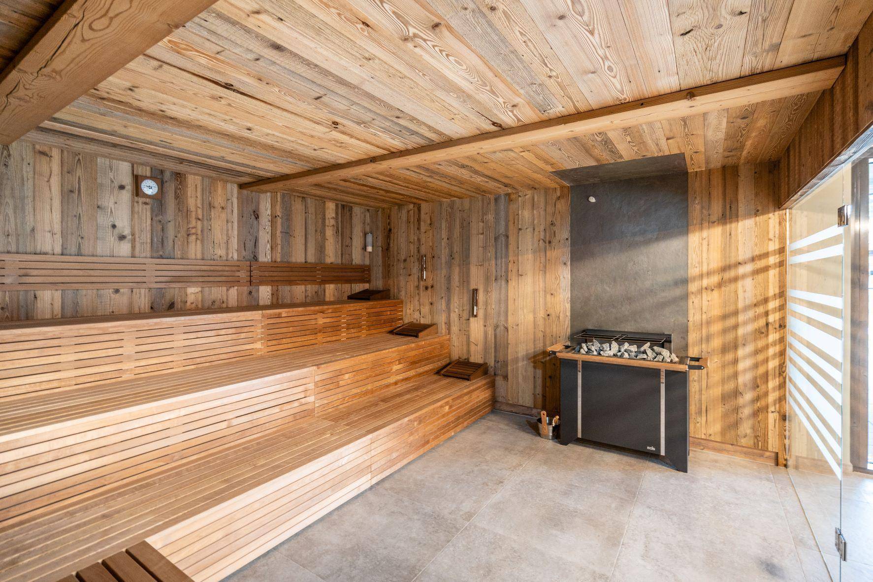 Geräumige Holzsauna mit mehreren Sitzebenen und modernem Saunaofen.