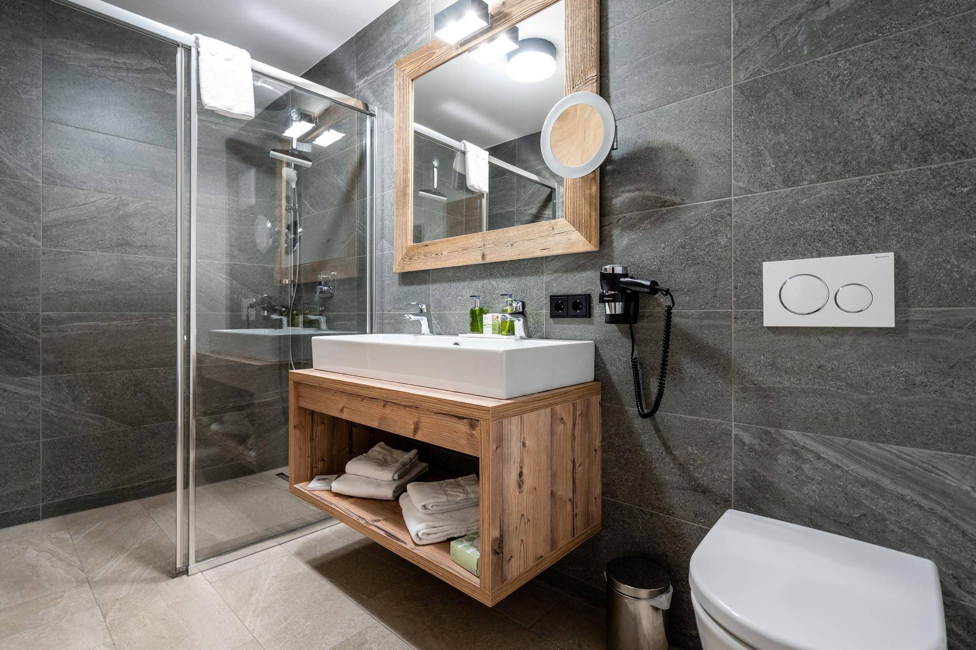 Elegantes Badezimmer mit Dusche, wandhängendem WC und Holzwaschtisch.