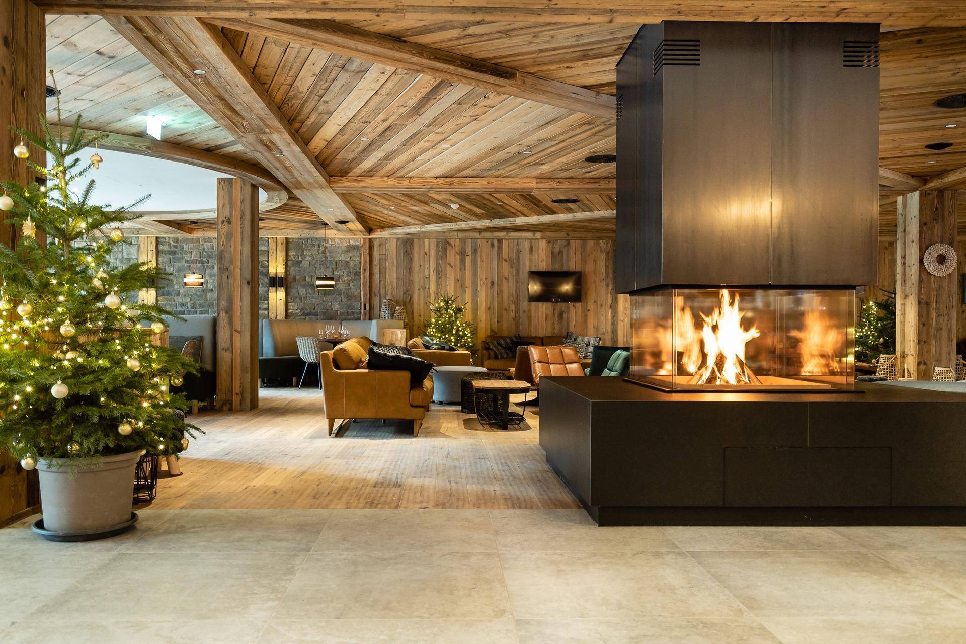 Gemütlicher Loungebereich mit modernem Kamin, Holzbalkendecke und festlicher Weihnachtsdekoration.