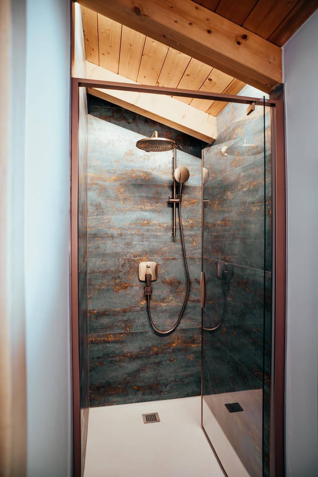 Moderne Dusche mit Regenduschkopf und schrägen Decken im Dachgeschoss.