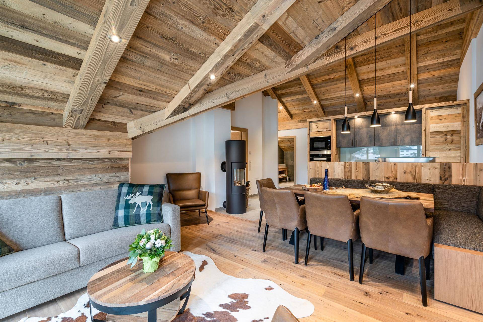 Geräumiger Wohn-Essbereich mit Holzbalkendecke, Kamin und offener Küche.