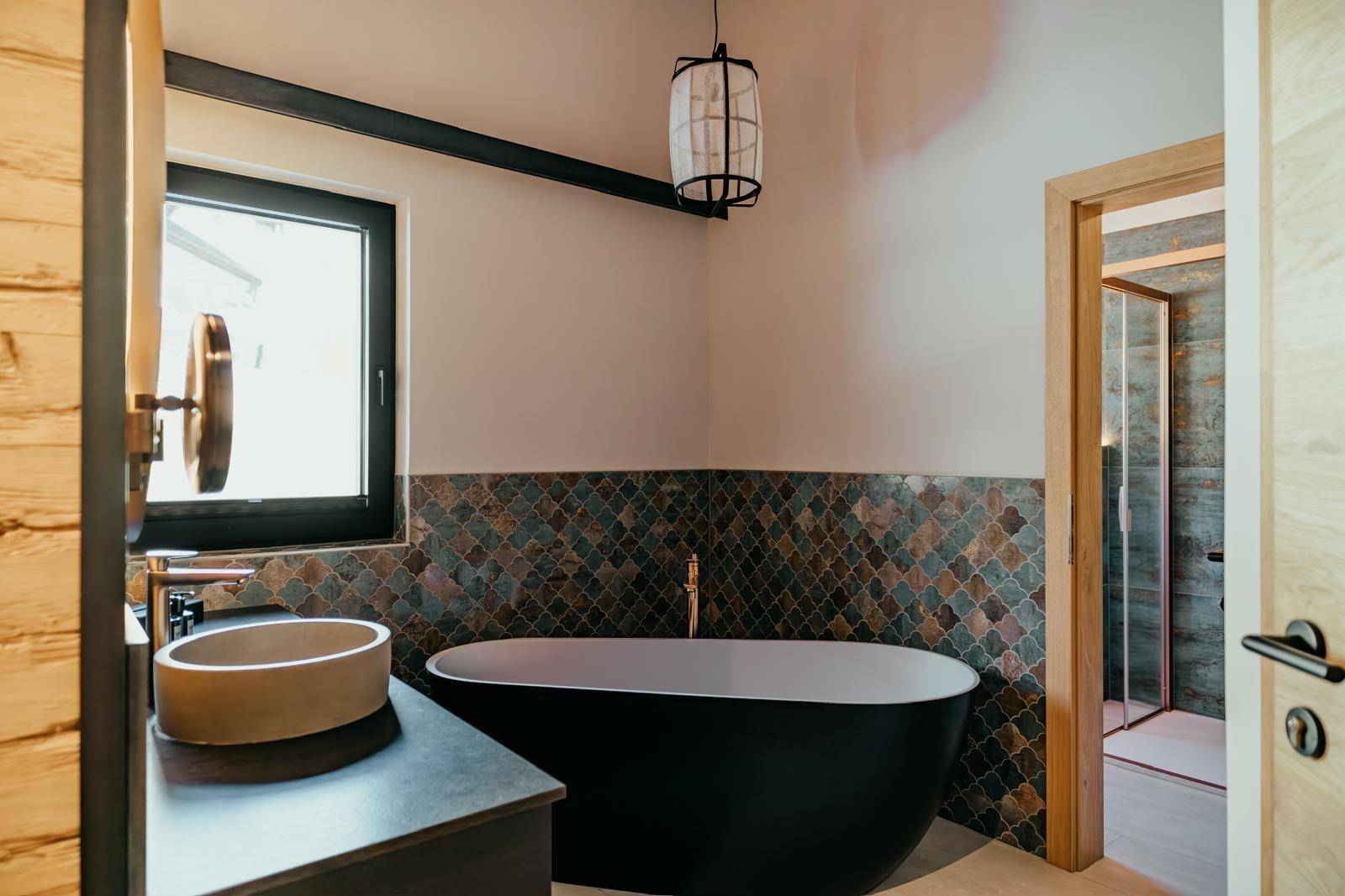 Stilvolles Badezimmer mit freistehender Badewanne, modernem Waschbecken und Fenster für Tageslicht.