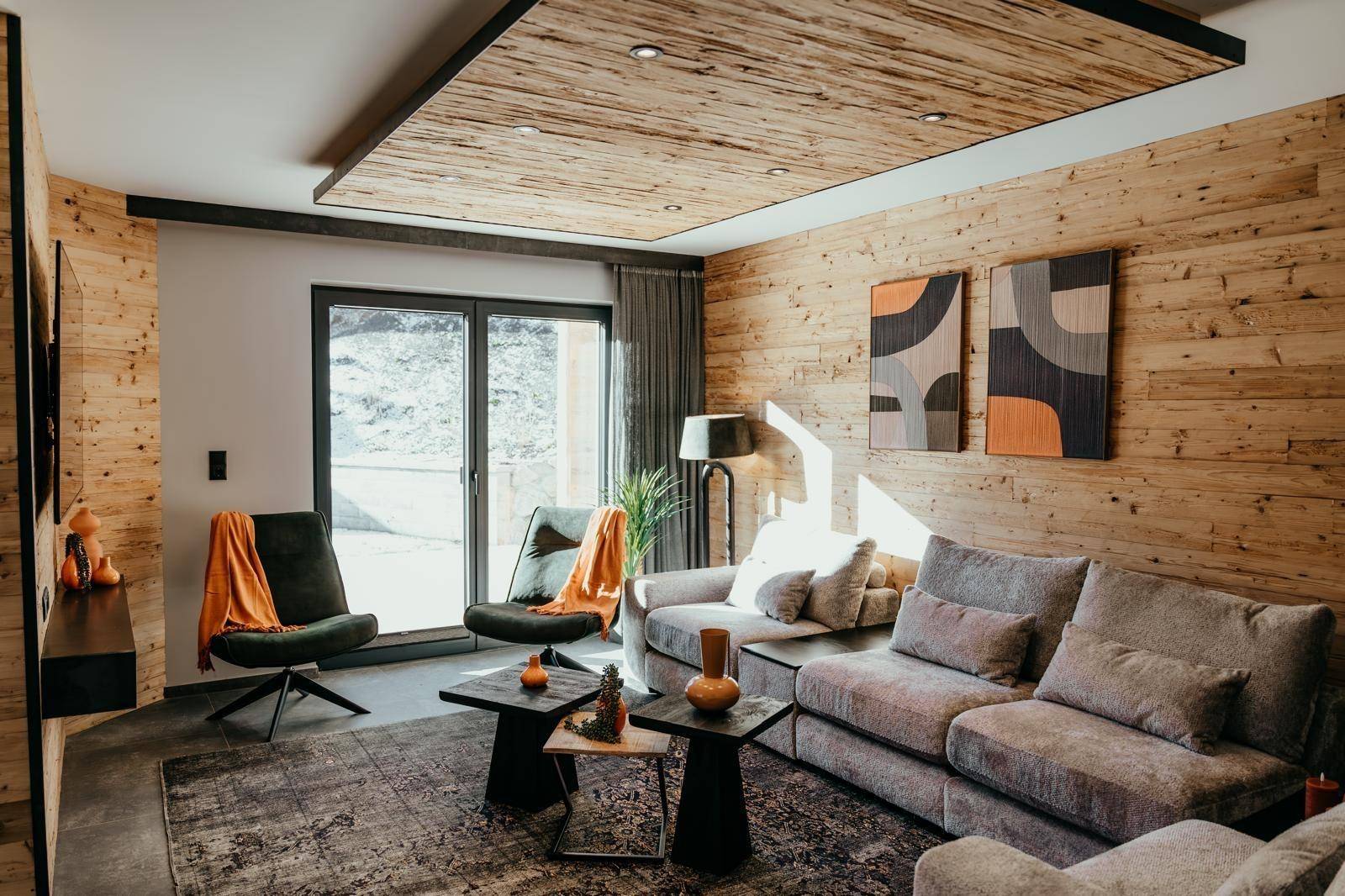 Helles Wohnzimmer mit Holzwänden, bequemen Sofas und großen Fenstern für viel Tageslicht.
