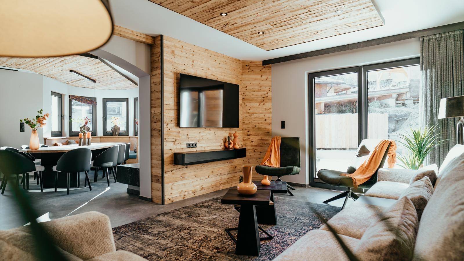 Gemütlicher Wohnbereich mit Holzwänden, modernem Dekor und großen Fenstern mit Zugang nach draußen.