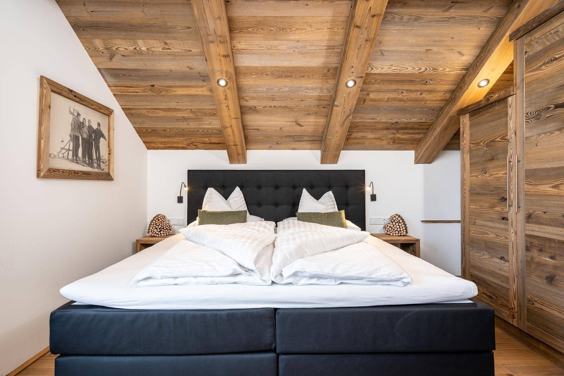 Gemütliches Schlafzimmer mit Holzbalkendecke, großem Bett und rustikalen Holzschränken.