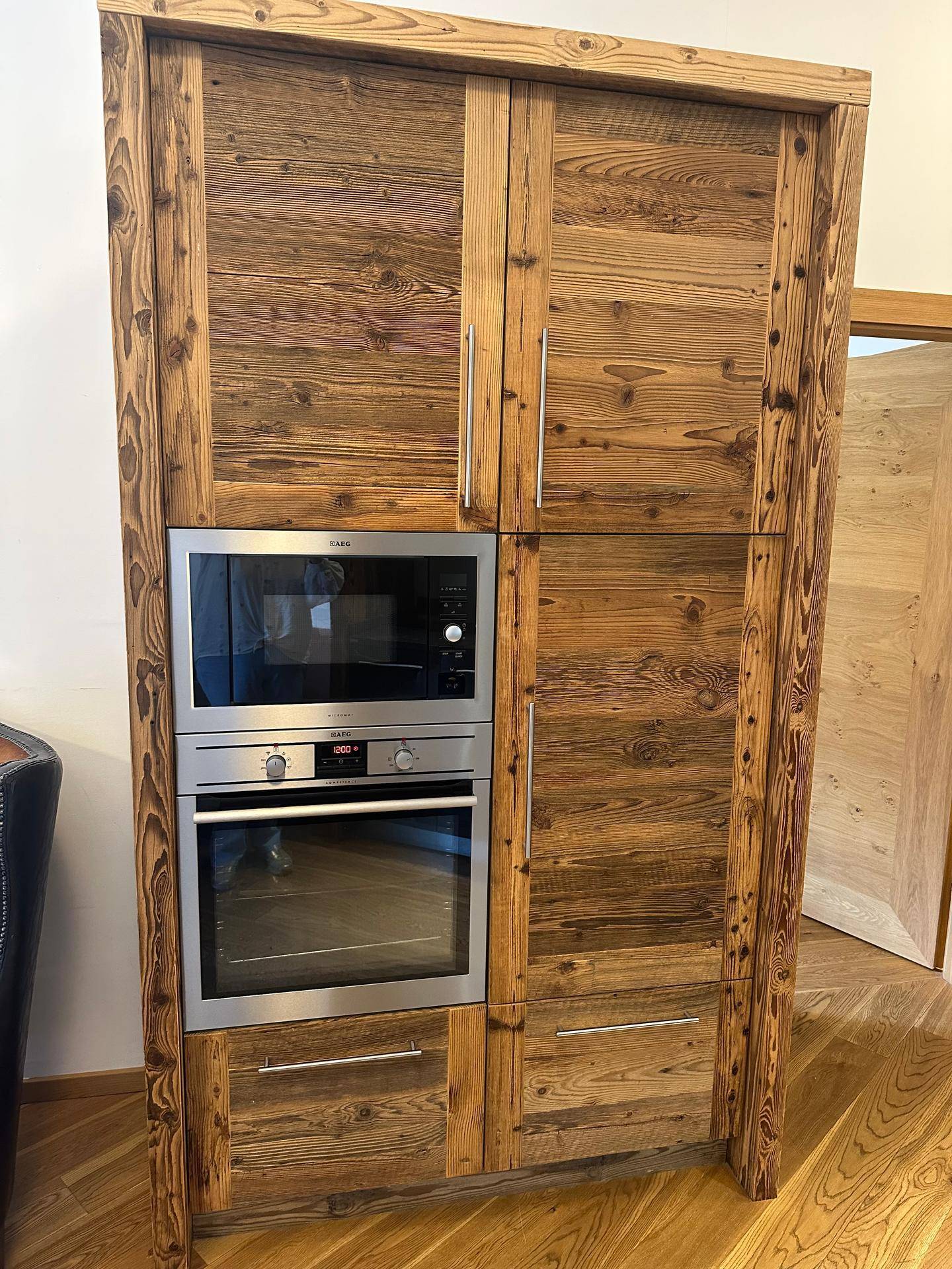 Integrierter Küchenschrank aus Altholz mit Backofen und Mikrowelle in einem modernen Design.