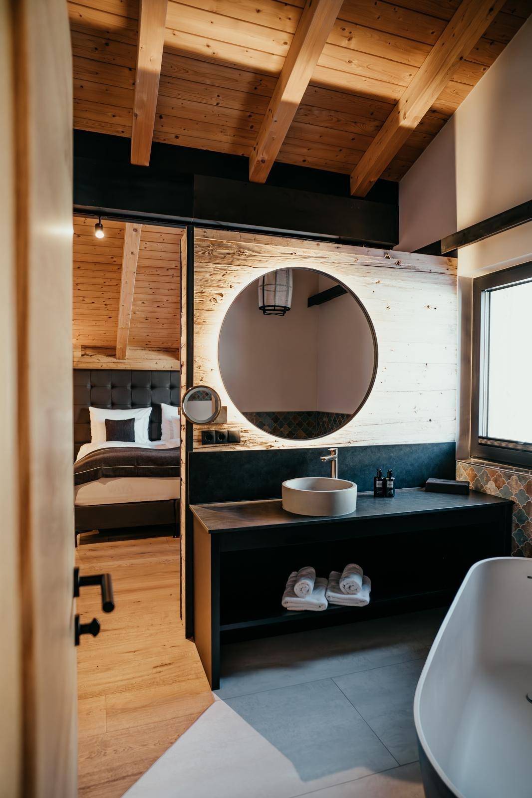 Geräumiges Schlafzimmer mit Holzwänden und offenem Zugang zum Badezimmer.