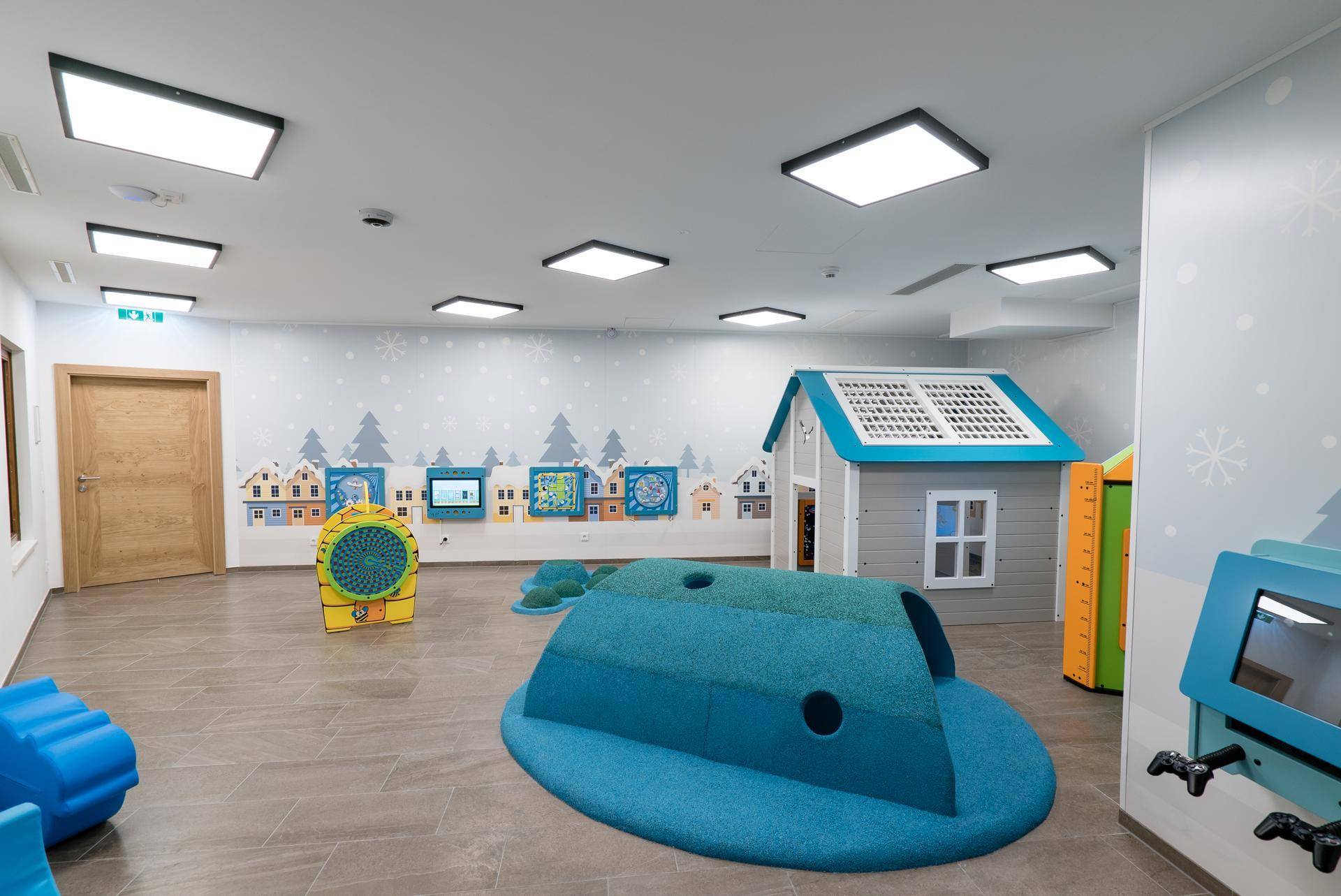 Heller Spielbereich für Kinder mit bunten Spielgeräten und Wanddekorationen in einem modernen Gebäude.