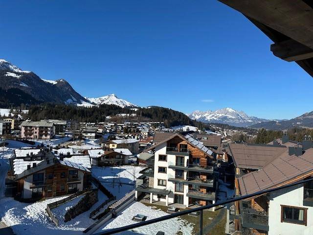 Panoramablick auf eine verschneite Berglandschaft mit Dorf und modernen Gebäuden.