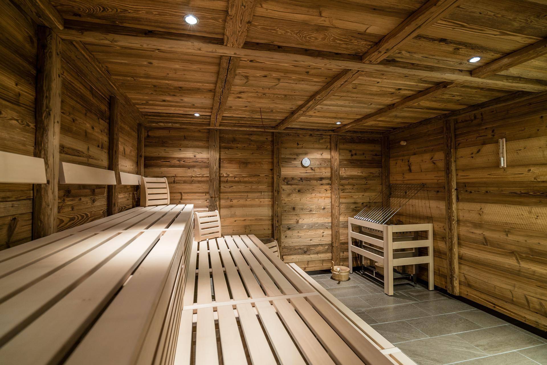 Geräumige Holzsauna mit mehreren Sitzebenen und einem traditionellen Saunaofen.
