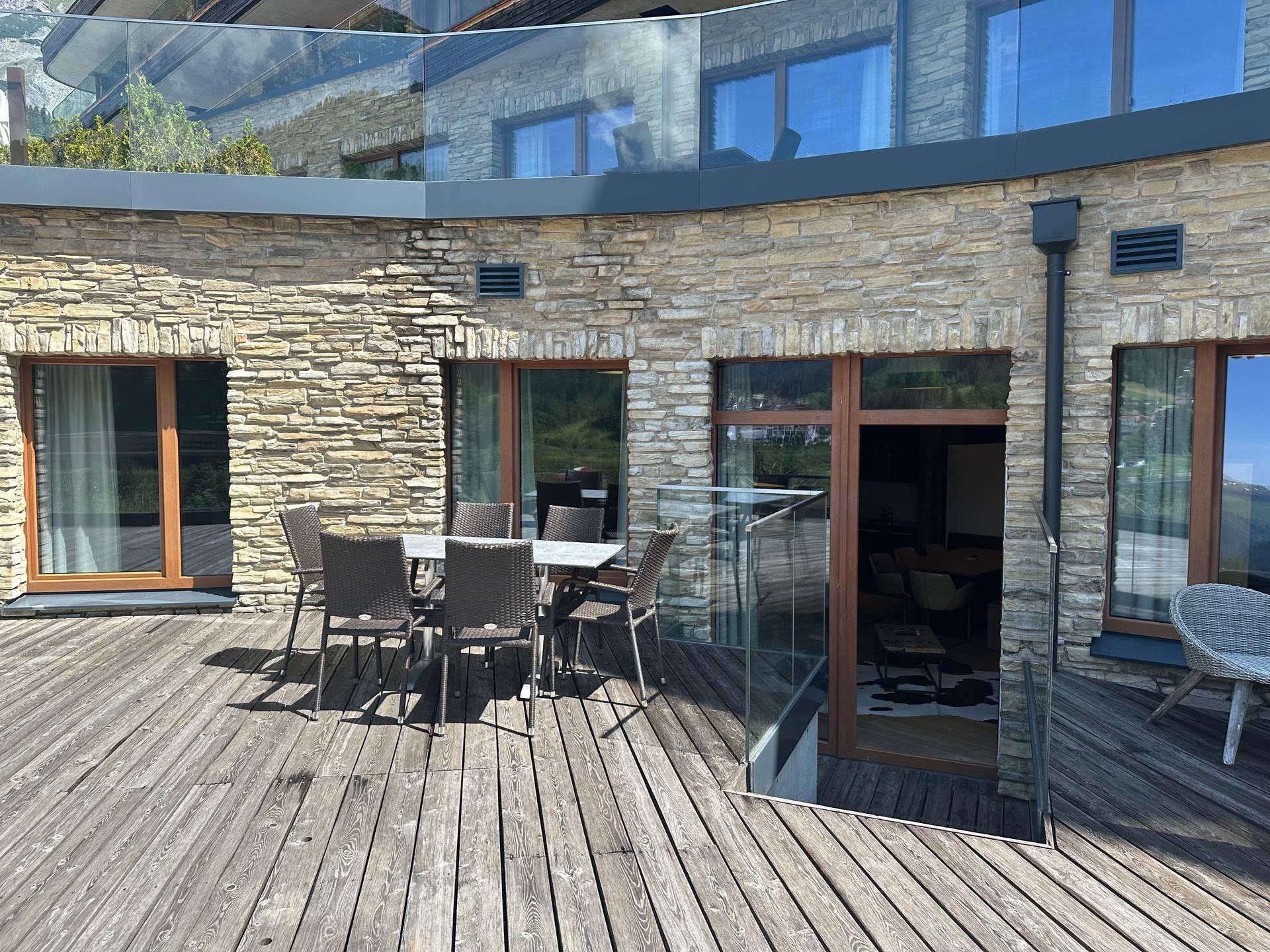 Große Holzterrasse mit Esstisch und Stühlen, ideal für Mahlzeiten im Freien mit Bergblick.