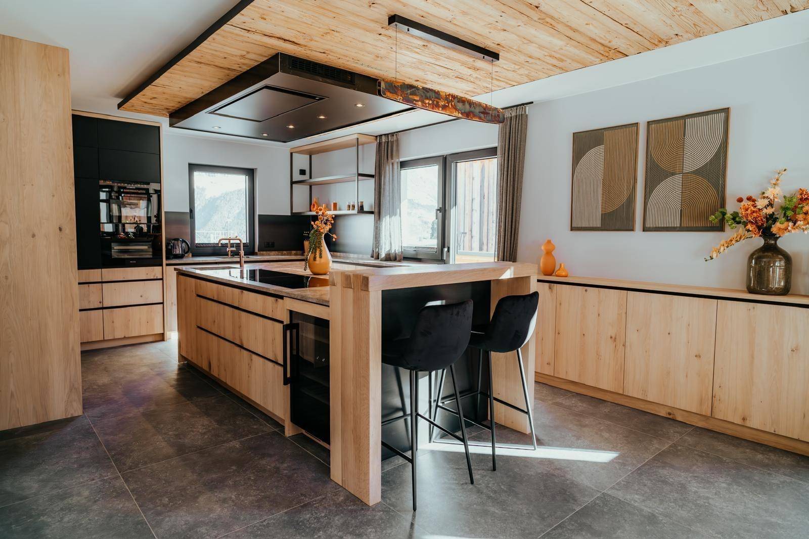 Geräumige moderne Küche mit Holzfronten, Kochinsel, Frühstücksbar und integriertem Weinkühler.