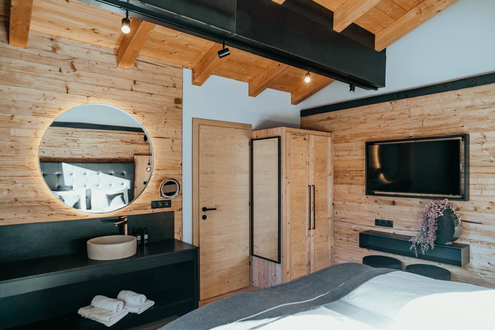 Gemütliches Schlafzimmer mit Holzwänden, integriertem Waschbecken und Fernseher.