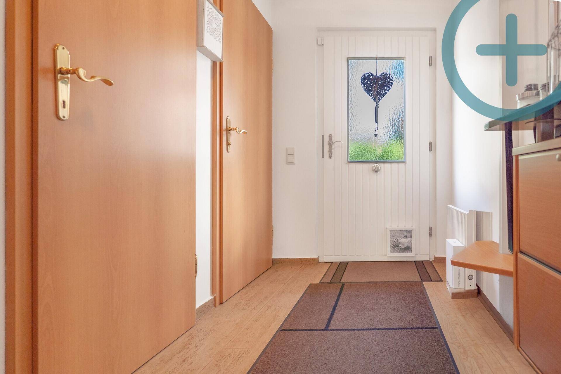 Heller Eingangsbereich mit Holztüren und einer Haustür mit dekorativem Glaseinsatz.